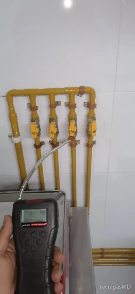 Detector de gas con sonda flexible sobre una derivación en tubería amarilla con cuatro válvulas de manija amarilla